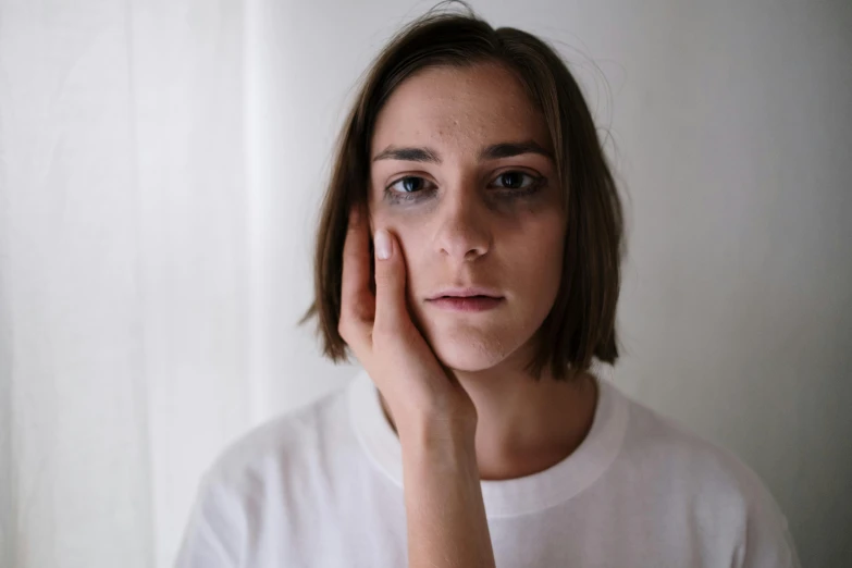 a woman holding her hand to her face, inspired by Elsa Bleda, trending on pexels, hyperrealism, boy thin face, plain walls |somber white eyes, depressed dramatic bicep pose, raised eyebrow