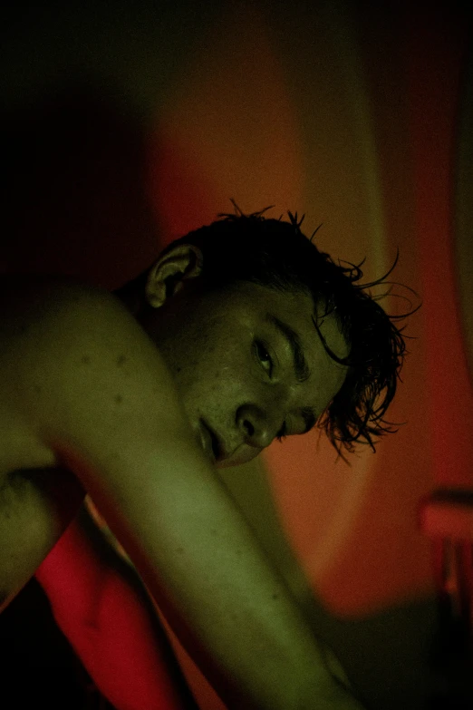 a man laying on a bed in the dark, digital art, inspired by Nan Goldin, bauhaus, sweaty wet skin, detailed red lighting, still from riverdale, teenage boy