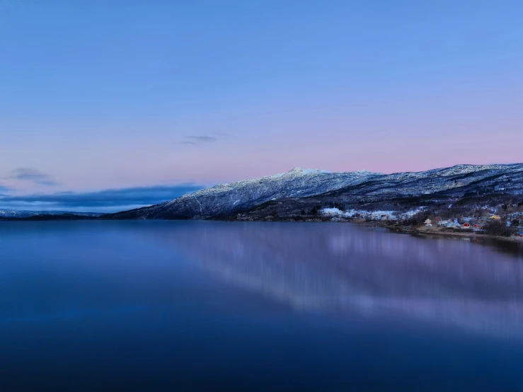 a body of water surrounded by snow covered mountains, by Eero Snellman, pexels contest winner, calm evening, shades of pink and blue, hamar, three - quarter view