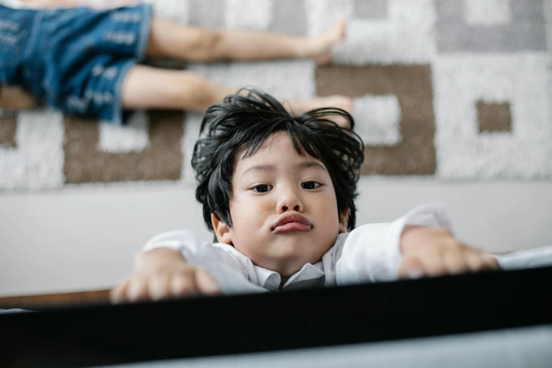 a little boy that is sitting in a crib, pexels contest winner, lying on back, detailed face of a asian boy, playing games, annoyed expression