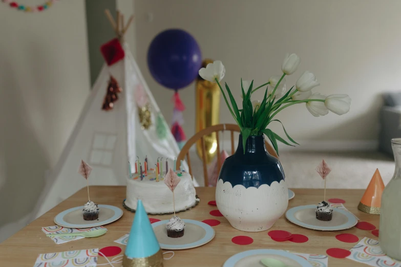 a wooden table topped with plates and cupcakes, by Alice Mason, pexels contest winner, teepee, party balloons, low quality photo, thumbnail