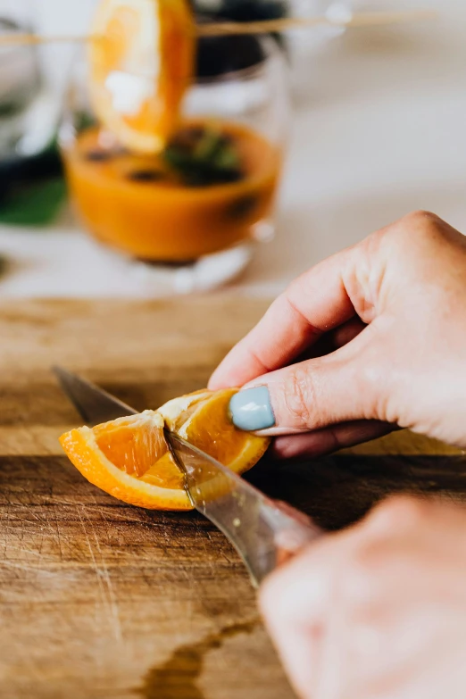 a person cutting an orange on a cutting board, pexels, holding a drink, 🦩🪐🐞👩🏻🦳, half turned around, loosely cropped