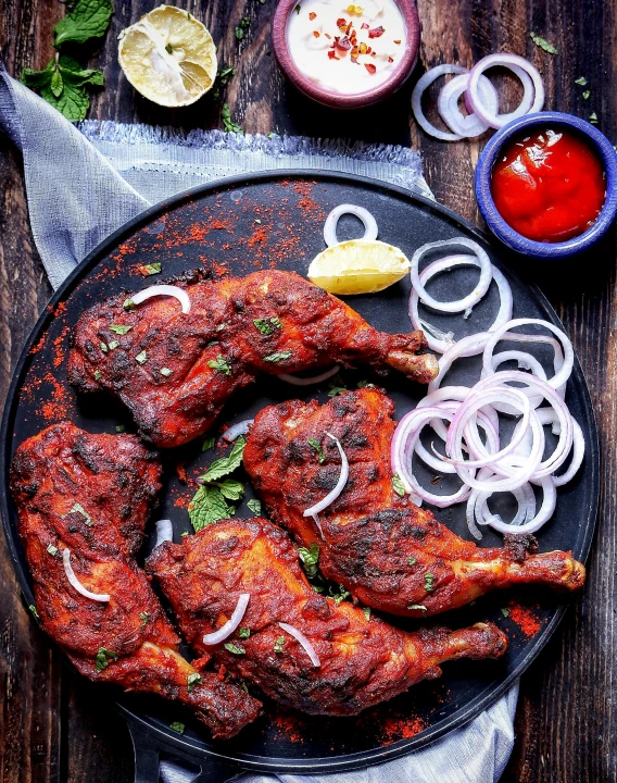 a black plate topped with chicken wings and onions, an album cover, by Julia Pishtar, pexels contest winner, hurufiyya, indian, 15081959 21121991 01012000 4k, grilled chicken, celebration