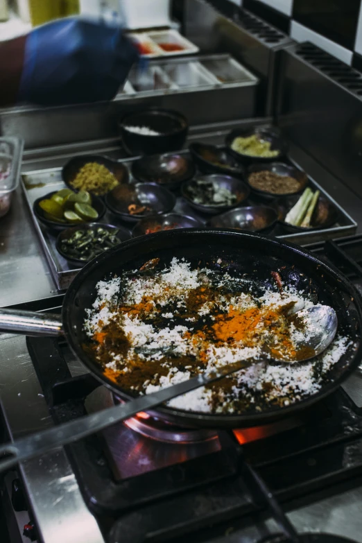 a frying pan filled with food sitting on top of a stove, sri lanka, chefs table, multiple stories, thumbnail