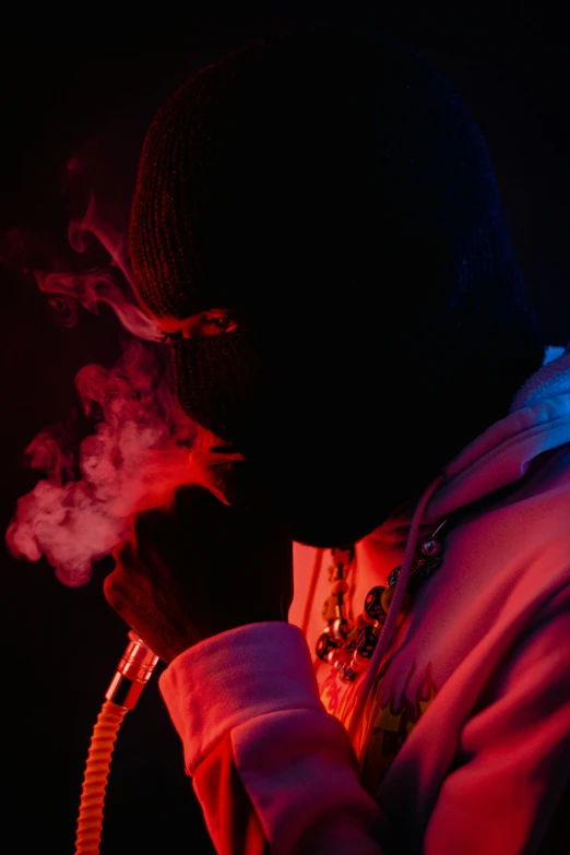 a man smoking a cigarette in the dark, an album cover, unsplash, chief keef, red and blue back light, balaclava, press photos