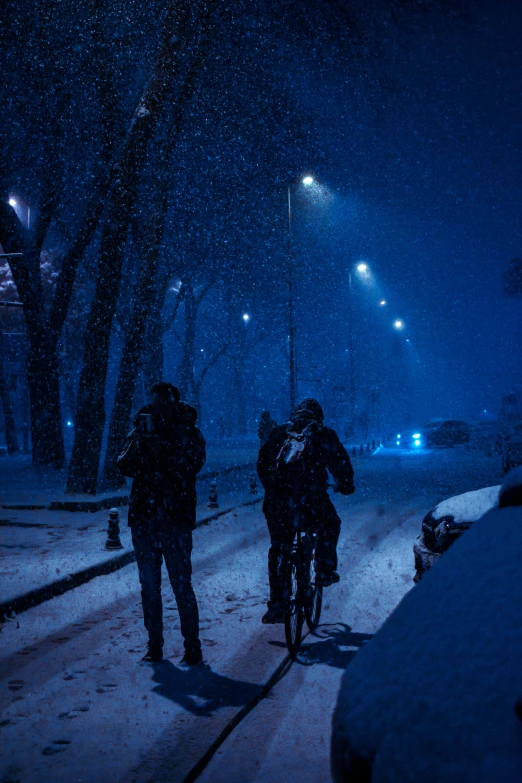 a group of people riding bikes down a snow covered street, by Tamas Galambos, unsplash contest winner, realism, blue night, profile pic, people walking around, background image