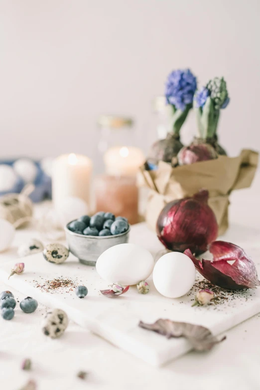 a white table topped with eggs and blueberries, a still life, unsplash, candles, background image, grape hyacinth, vintage photo