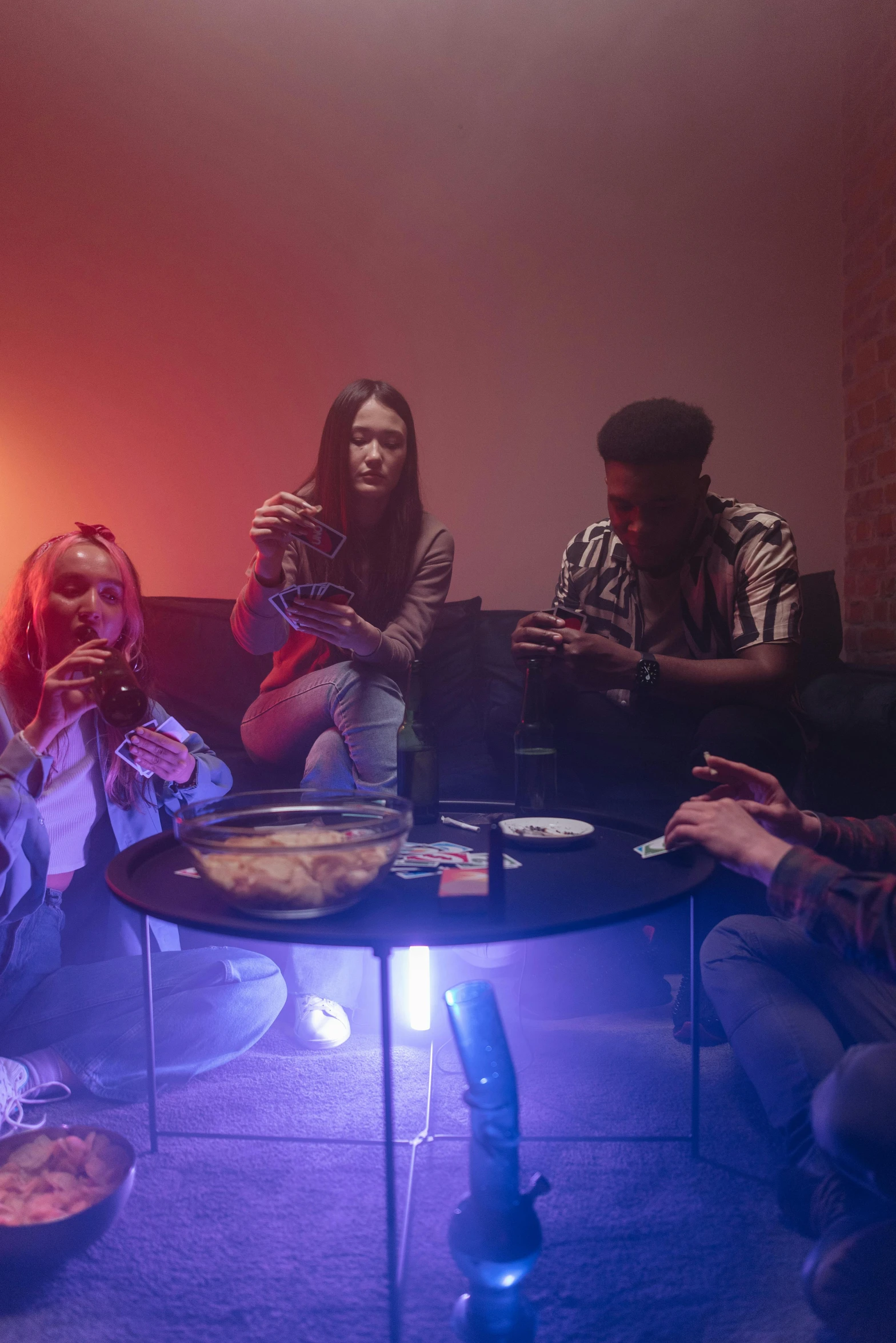 a group of people sitting around a table, inspired by Nan Goldin, pexels, renaissance, 4 cannabis pots, psychedelic lighting, ( ( theatrical ) ), lounge