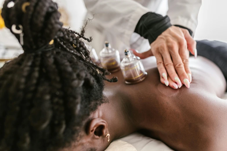 a woman getting a back massage at a spa, by Meredith Dillman, trending on pexels, black human spine, partially cupping her hands, gold and white robes, coloured