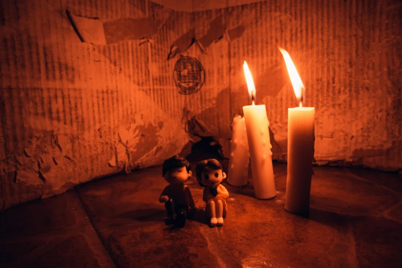 a couple of candles sitting next to each other, an album cover, by Elsa Bleda, pexels contest winner, several dolls in one photo, silent hill game, cardboard, inside haunted house