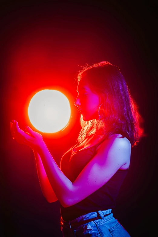 a woman holding a glowing ball in her hand, an album cover, by Adam Marczyński, unsplash contest winner, light and space, theatrical lighting, red moon, female magician, profile picture 1024px