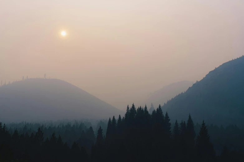 the sun is setting over a mountain range, unsplash contest winner, tonalism, industrial fires and smog, black fir, hazy, boreal forest