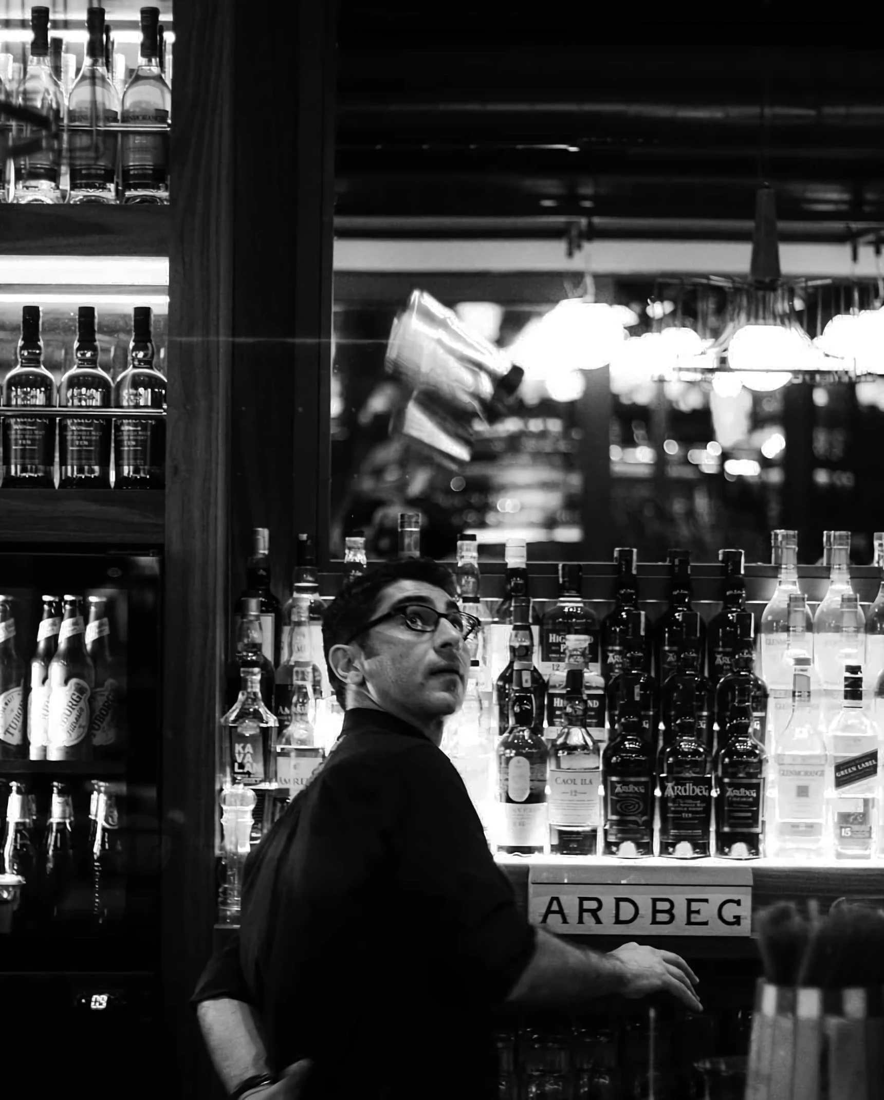 a black and white photo of a man sitting at a bar, inspired by Bert Hardy, happening, reza afshar, whisky, instagram post, hibbary!!