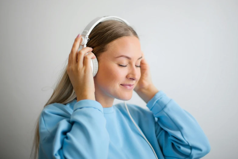 a woman wearing headphones listening to music, trending on pexels, wearing a light blue shirt, hypnosis, avatar image, warm and gentle smile