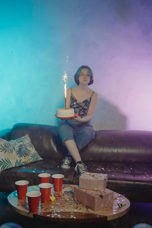 a woman sitting on a couch holding a birthday cake, an album cover, inspired by Elsa Bleda, pexels contest winner, bisexual lighting, at a birthday party, movie still, low quality photo