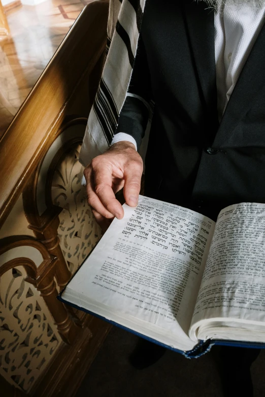 a man in a suit is reading a book, by Daniel Lieske, trending on unsplash, unilalianism, holy ceremony, hebrew, 15081959 21121991 01012000 4k, instagram post