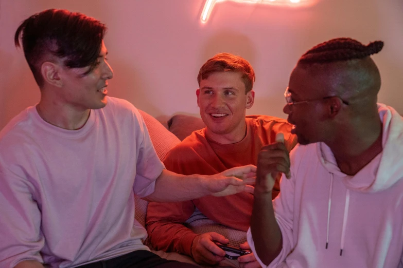 a group of men sitting next to each other on a couch, pexels, neon accent lights, smiling at each other, playing games, charli bowater and artgeem