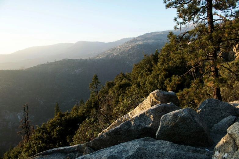 a couple of large rocks sitting on top of a mountain, by Joe Stefanelli, dappled in evening light, overlooking a valley with trees, in avila pinewood, slide show