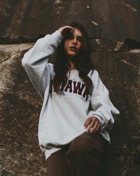 a woman leaning against a rock with her hand on her head, inspired by Hannah Frank, trending on unsplash, graffiti, wearing sweatshirt, grainy vintage, at college, ( ( ( kauai ) ) )