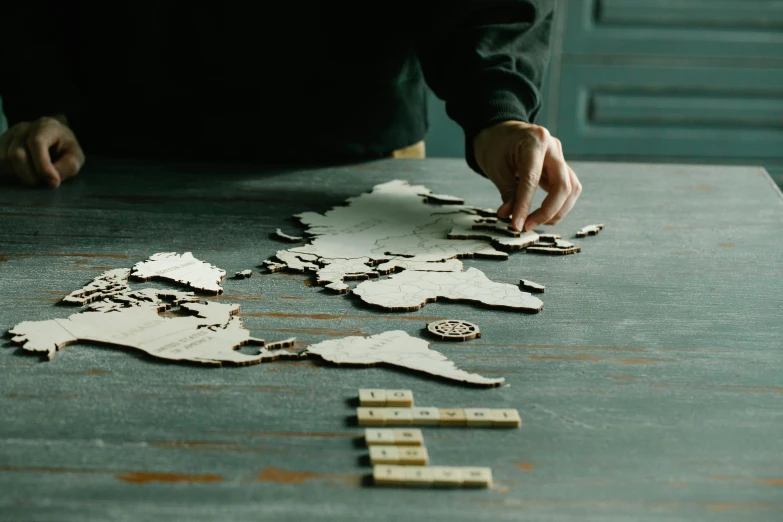 a person playing a game of scrabbles on a table, a jigsaw puzzle, pexels contest winner, interactive art, world map, laser cut, all these worlds are yours, ash thorp