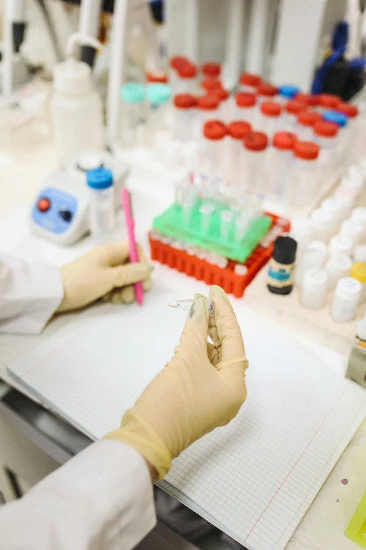 a person in a lab coat writing on a piece of paper, pathology sample test tubes, thumbnail, hands on counter, colour corrected