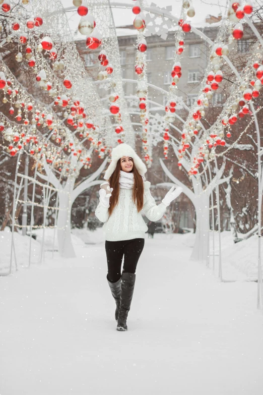 a woman walking through a snow covered park, by Julia Pishtar, pexels contest winner, excited russians, 💋 💄 👠 👗, in front of white back drop, cozy lights