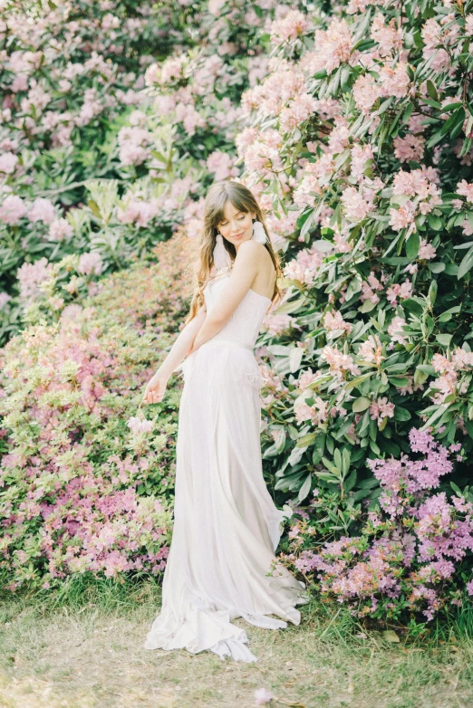 a woman standing in front of a bush of flowers, inspired by Oleg Oprisco, unsplash, wedding photo, sydney sweeney, doing an elegant pose over you, “ ethereal