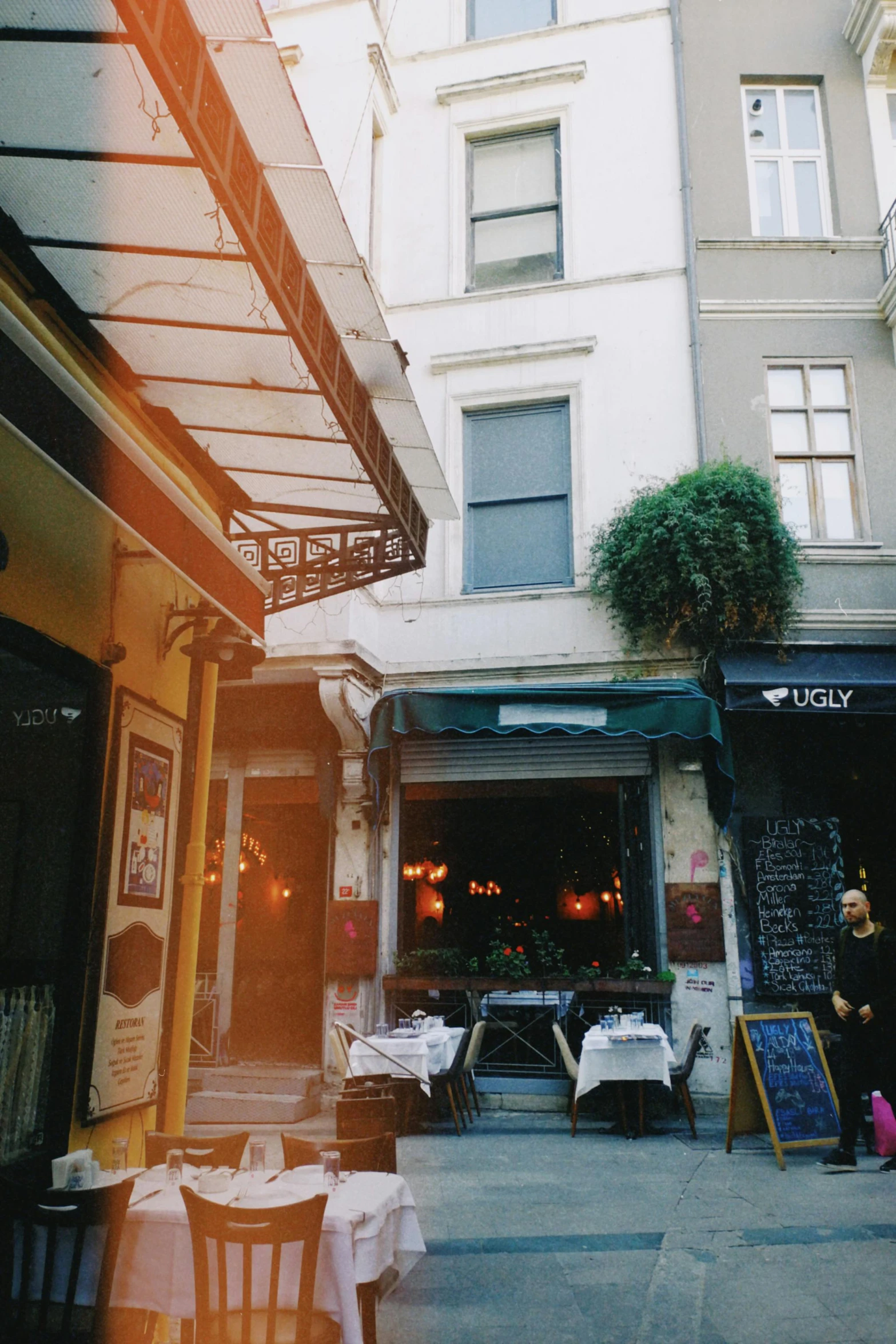 a group of people sitting at tables outside of a restaurant, a polaroid photo, by Cafer Bater, unsplash, art nouveau, istanbul, french village exterior, gif