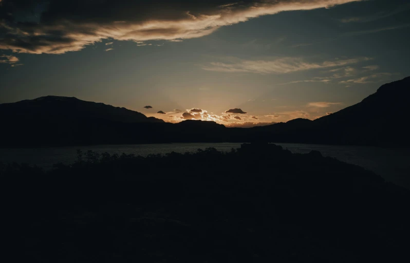 the sun is setting over a body of water, by Lee Loughridge, unsplash contest winner, hills in the background, on black background, trending on vsco, lachlan bailey