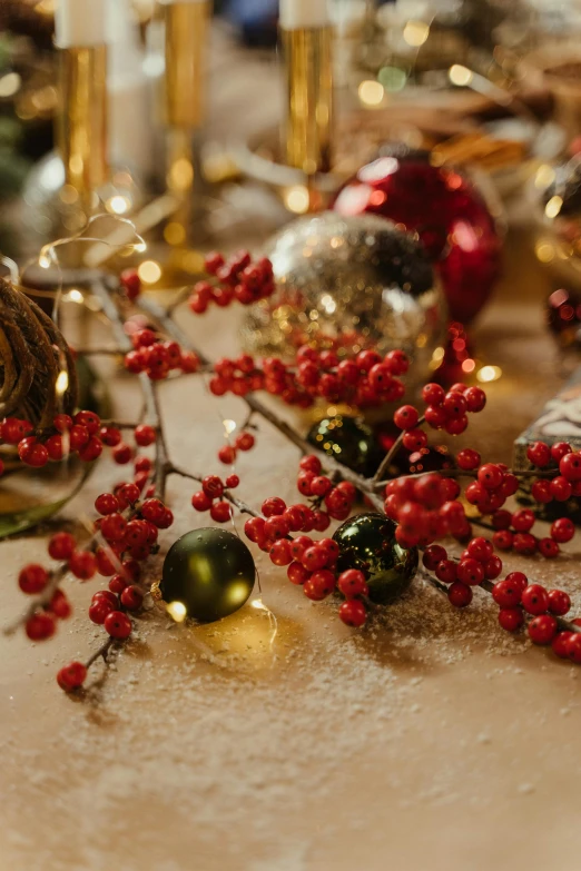 a table topped with christmas decorations and candles, a still life, trending on pexels, berries dripping, detail shot, golden glow, red and green