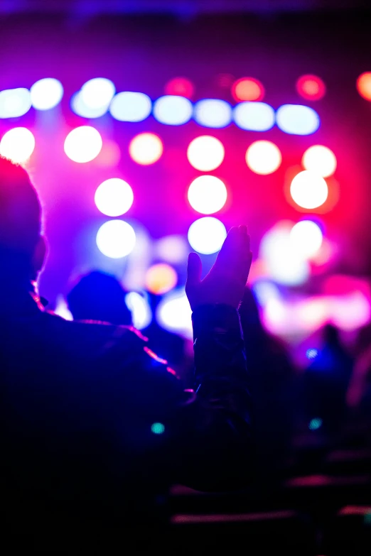 a group of people that are standing in front of a stage, pexels, happening, bokeh. brian spilner, red and blue black light, pictured from the shoulders up, purple and yellow lighting