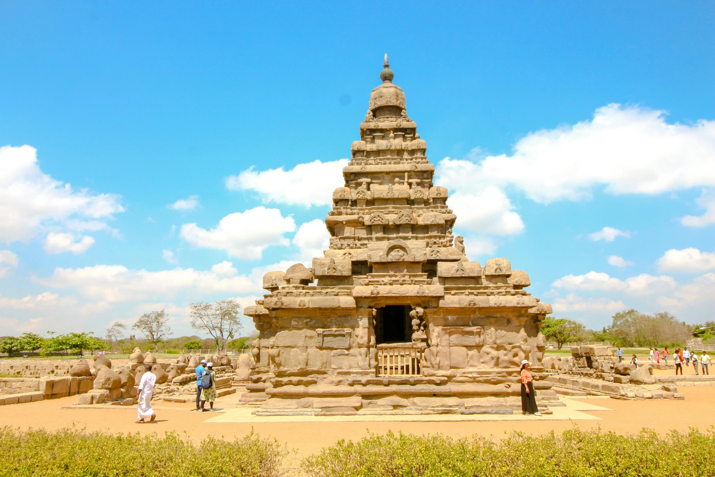 a group of people standing in front of a stone structure, a statue, pexels contest winner, kerala motifs, blue sky, square, sandcastle