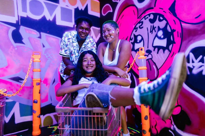 a group of people sitting on top of a shopping cart, a portrait, pexels contest winner, graffiti, neon lights in the background, happy family, teenage girl, essence