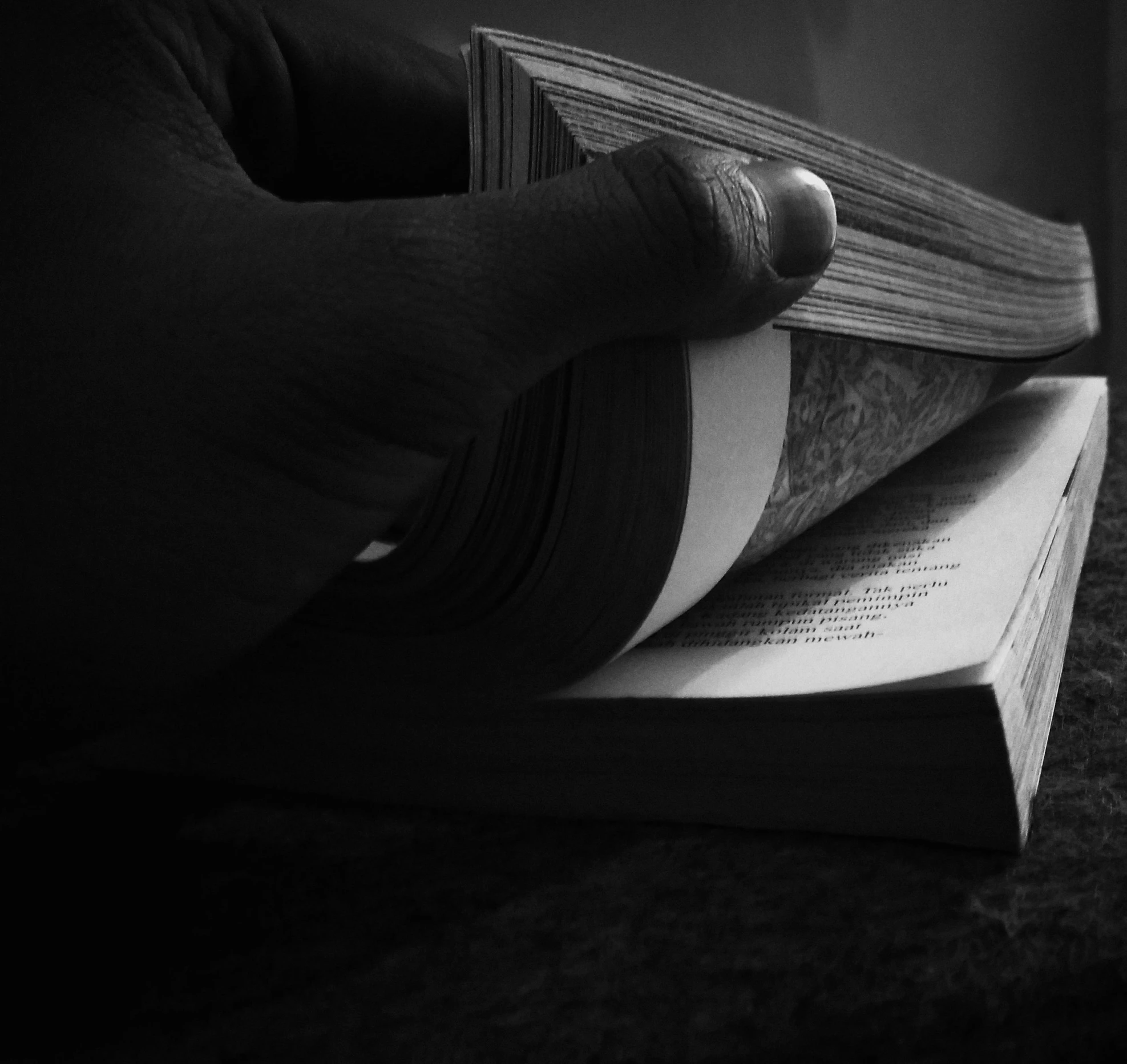a person holding a book in their hand, a black and white photo, by Stefan Gierowski, pixabay, realism, bending down slightly, 2000s photo, finger, hyperdetailled