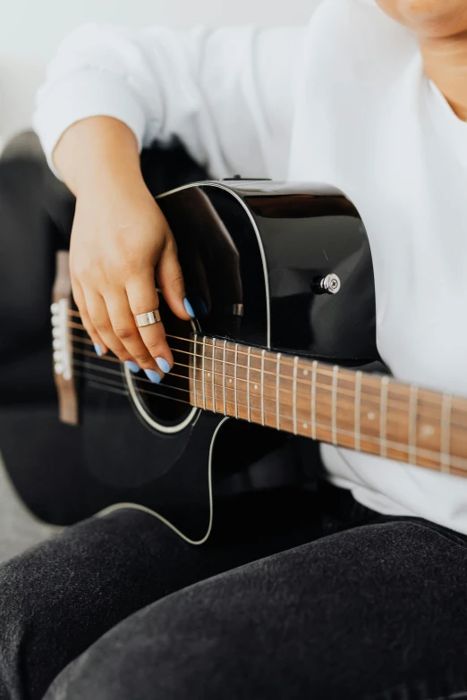 a woman sitting on a couch playing a guitar, trending on unsplash, on grey background, close - up on detailed, zoomed out, no - text no - logo