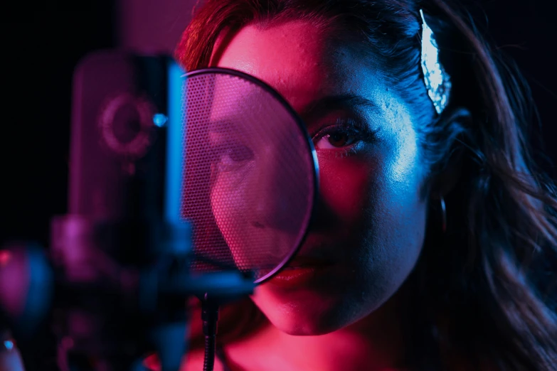 a woman looking through a magnifying glass, an album cover, inspired by Elsa Bleda, trending on pexels, holography, singing into microphone, cinematic studio lighting, red and blue lighting, standing microphones