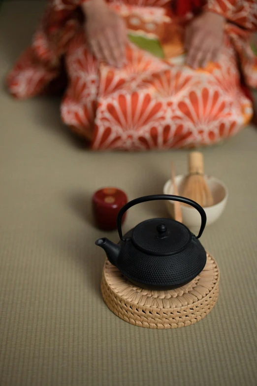 a close up of a tea pot on a table, inspired by Sesshū Tōyō, unsplash, textiles, square, figure meditating close shot, black