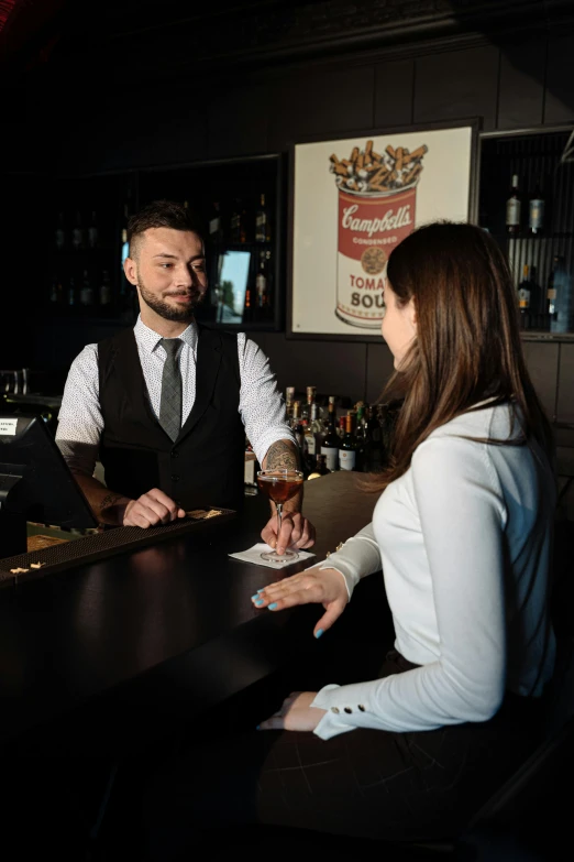 a man and a woman sitting at a bar, at checkout, against dark background, thumbnail, staff