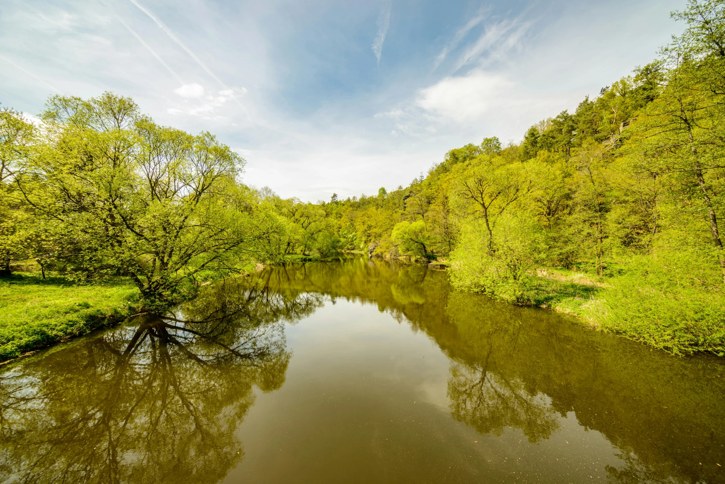 a river running through a lush green forest, by Sebastian Spreng, pexels contest winner, romanticism, lower saxony, a photo of a lake on a sunny day, marvellous reflection of the sky, radoslav svrzikapa