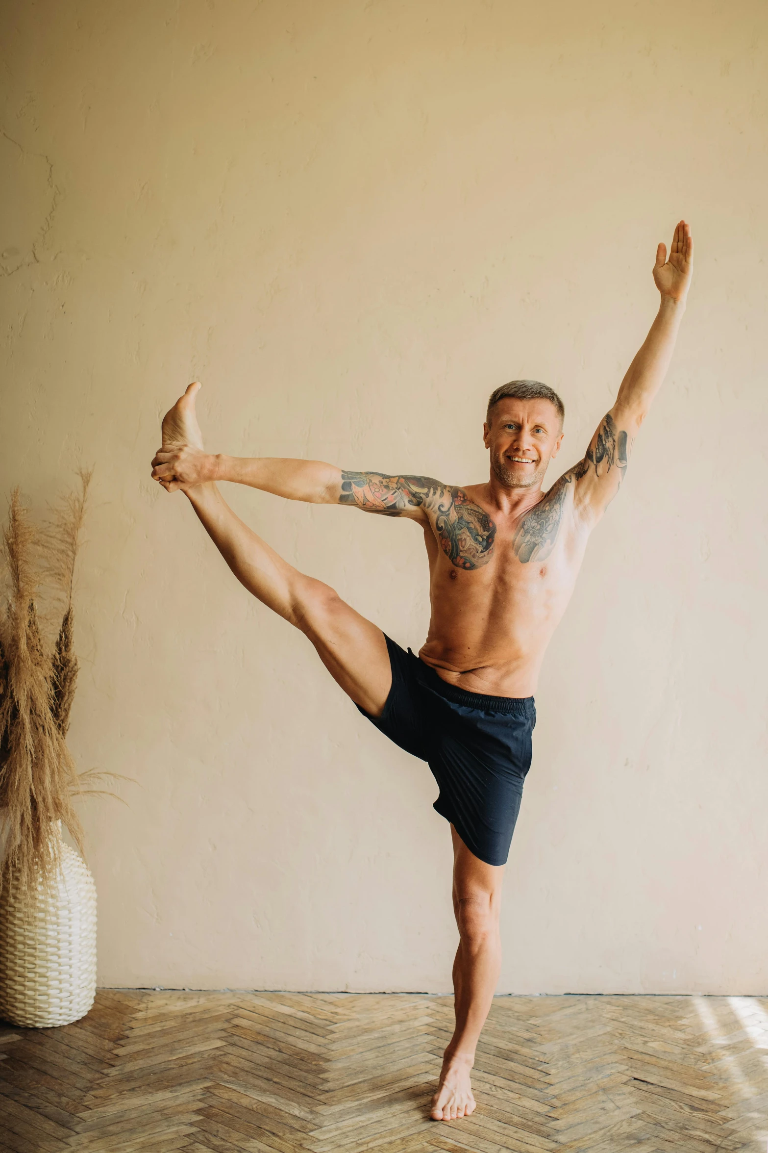 a man standing in the middle of a yoga pose, a photo, arabesque, lean man with light tan skin, shows a leg, davey baker, 4 5 yo