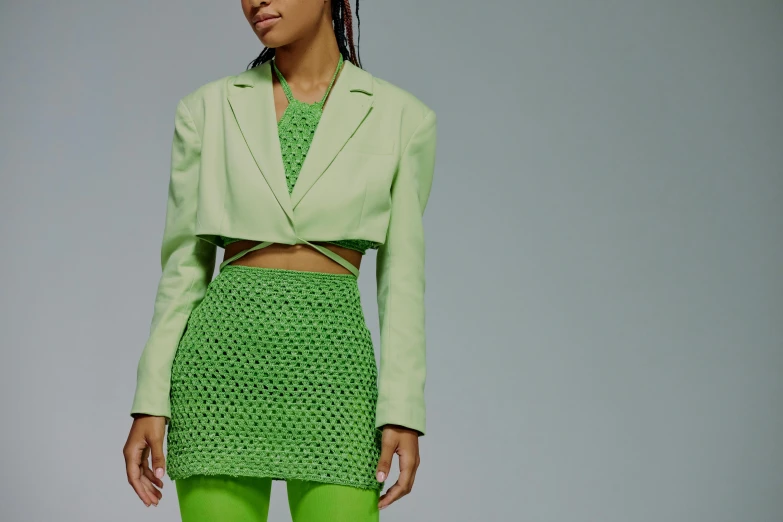 a woman in a green skirt and jacket, inspired by Olivia Peguero, trending on pexels, neon colored suit, on textured base; store website, wearing crop top and miniskirt, trending on dezeen