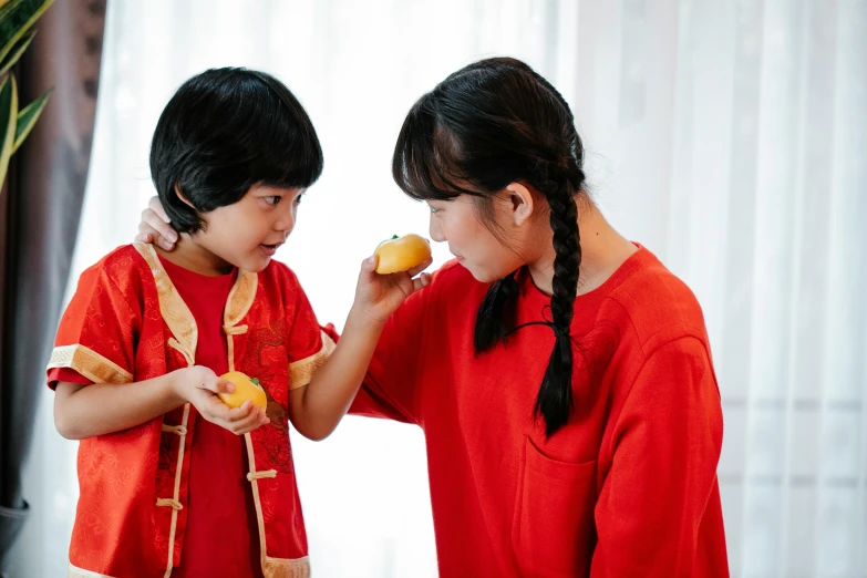 a couple of kids standing next to each other, inspired by Ni Duan, pexels contest winner, she is eating a peach, wearing red attire, avatar image, performance