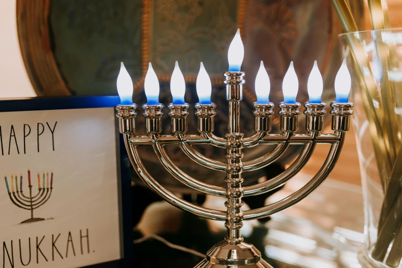 a silver menorah sitting on top of a table, by Julia Pishtar, trending on unsplash, fan favorite, torches on wall, with names, festive atmosphere