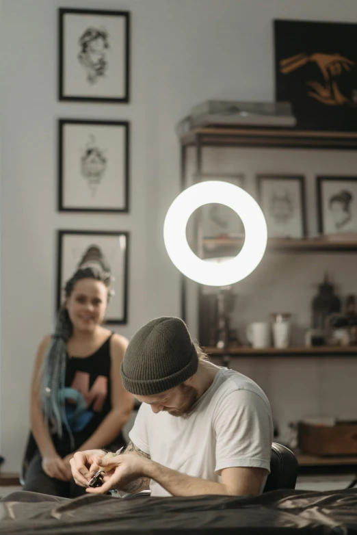 a man sitting at a table working on a piece of art, a tattoo, trending on pexels, ring light, hanging out with orbs, portrait of two people, instagram picture