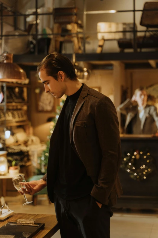 a man standing in a store holding a glass of wine, pexels contest winner, happening, avan jogia angel, festive atmosphere, colin farrell, sad scene