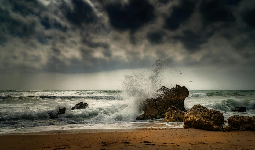 a large body of water sitting on top of a sandy beach, pexels contest winner, romanticism, sea storm, rocks falling, turbulence, mediterranean