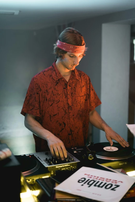 a man that is playing some kind of music, an album cover, unsplash, dj at a party, caspar david, wearing a headband, red cloth around his shoulders