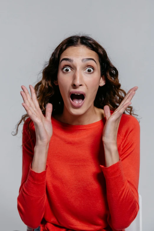 a woman with a surprised look on her face, pexels, antipodeans, ross geller screaming, hands down, square, plain background