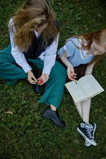 a couple of girls sitting on top of a lush green field, inspired by Elsa Beskow, renaissance, wearing school uniform, close-up on legs, holding grimoire, 2019 trending photo