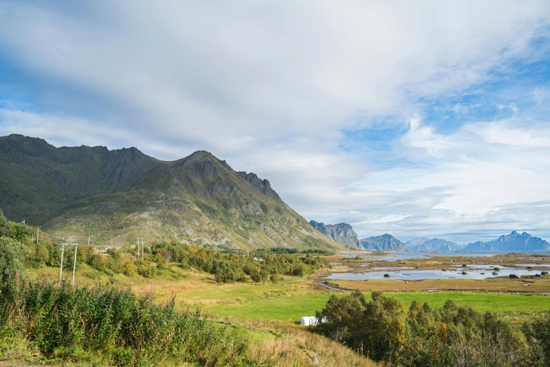 a grassy field with mountains in the background, by Roar Kjernstad, unsplash, hurufiyya, inlets, conde nast traveler photo, october, geology